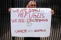 Seorang pencari suaka asal Somalia membawa poster penolakan diskriminasi dalam aksinya di depan kantor perwakilan UNHCR di Makassar.