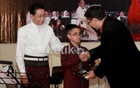 Fadli nampak memberikan bukunya kepada cucu Idris yang juga berbakat bermain biola.
