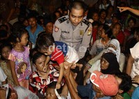 Seorang polisi mengevakuasi serang anak kecil dari tangan orang tuanya yang sedang mengantri daging kurban, antrian yang berdesak-desakan ini membahayakan anak-anak. (Ramses/detikcom)