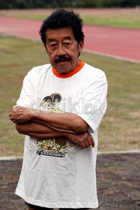 Bob Hasan terlihat santai dengan mengenakan kaos putih bergambar wayang dan celana pendek.