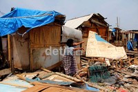 Warga mencari barang-barang yang masih layak pakai di antara puing-puing rumah.