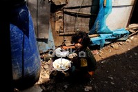 Dira (9), mengambil nasi dari panci di luar rumahnya yang tergusur.
