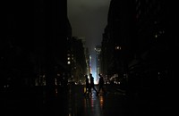 Tiga orang warga melintas di jalanan yang gelap akibat pemadaman listrik di  Manhattan, New York.