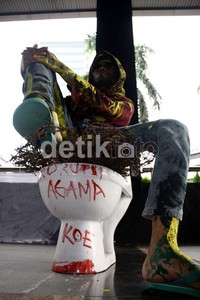 Seorang pendemo duduk di atas closet saat melakukan aksi teatrikal di depan gedung KPK, Jakarta. (Ramses/detikcom).