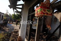 TNI membersihkan puing-puing dari rumah yang dibakar massa.