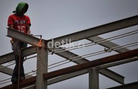 Seorang pekerja mengelas bagian atap halte.