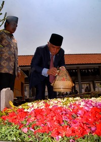Hatta Rajasa menaburkan bunga di makam Gus Dur. (Suhendra).