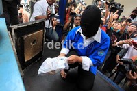 Tersangka memasukkan barang bukti ke alat penghancur.