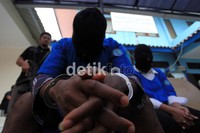 Para tersangka tampak tertunduk malu saat para wartawan memotret mereka.