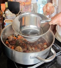Setelah ayam dan sayuran ditiriskan, kuah red wine masih bercampur dengan darah ayam. Untuk memisahkannya, air tersebut direbus terlebih dahulu dan gumpalan darah dibuang. Barulah red wine disaring. (Fitria Rahmadianti/Detikfood)