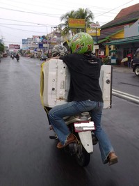 Orang yang dibonceng di belakang harus menahan dirinya dan mesin cuci. (Foto Dwi Janto Suandaru).