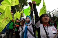 Beberapa buruh berorasi sambil mengepalkan tangan.