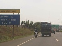 Sementara pengendara motor ini yang berboncengan terlihat sedang melintas di sebelah truk pengangkut galon mengarah ke gerbang tol Pondok Ranji. (Foto Ady Bramasto).