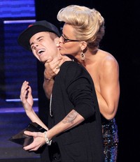 Jenny McCarthy mengecup Justin Bieber di atas panggung. Kevin Winter/Getty Images.