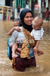 Warga menerobos banjir sambil menggendung 2 anaknya.