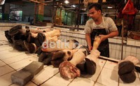 Seorang pedagang daging, menata kaki-kaki sapi yang hendak dijual. Kini beberapa pedagang beralih hanya menjual kaki-kaki sapi, dikarenakan mahalnya daging sapi.