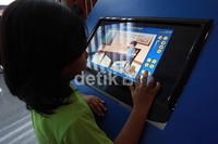 Seorang anak memperhatikan cara kerja software pendidikan.