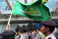 Para pendemo mengibarkan bendera Anshor di depan polisi yang berjaga.