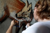 Seorang seniman Jerman tampak asyik membuat mural bergambar anjing.