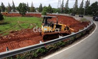 Sebuah alat berat sibuk meratakan jalan.