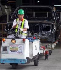 Seorang pekerja mempersiapkan bodi mobil.