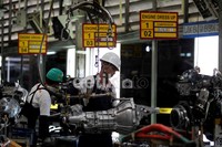 Seorang pekerja merakit mesin mobil.