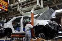 Seorang pekerja melakukan pengecatan eksterior mobil.