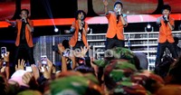 Coboy Junior kompak berkostum oranye saat beraksi di atas panggung.