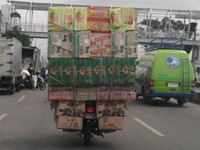     Pengendara motor berisikan kardus-kardus ini sedang melintas di Jalan Raya Bekasi, depan pasar Cakung. (Foto: Subkhan Budianto)