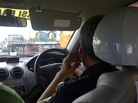 Supir taksi ini sedang larut dalam obrolan asik di telepon sampai tidak memikirkan keselamatan dan kenyamanan penumpang. (Foto: M Ikhsan)