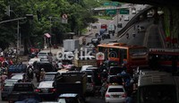 Pengendara mobil maupun motor saling mendahului di perempatan Jalan Ahmad Yani, Cempaka Putih, Jakarta.