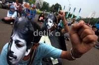 Beberapa pendemo memakai topeng bergambar Munir.