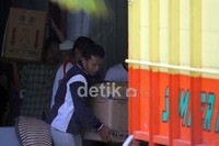 Beberapa orang turut sedang mengangkat barang-barang pribadi Andi dari rumah dinas ke dalam truk yang akan dibawa kembali ke rumah pribadinya.