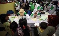  Seorang anak kecil datang menuju meja pendaftaran untuk ikut memeriksakan diri dengan didampingi orang tuanya.