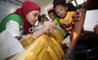     Seorang dokter muda sedang memeriksakan kaki pasien anak kecil yang terluka.