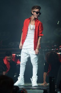 Justin tampil dibalut atasan, celana, dan sepatu putih yang dipadukan dengan kemeja merah. Michael Kovac/Getty Images for Jingle Ball 2012.