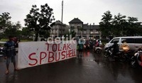 Warga membentang spanduk tuntutan di tengah jalan.