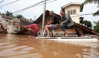 Warga menumpang perahu buatan untuk mengarungi banjir.