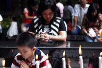 Seorang anak berdoa di depan lilin yang dipasang di altar Jesus Kristus, Gereja Katedral.