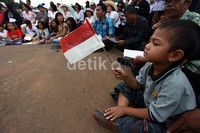 Sambil mengikuti misa, seorang anak kecil mengibarkan bendera Merah Putih.