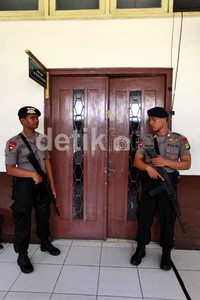 Dua orang polisi bersenjata laras panjang berjaga di depan ruang sidang Pengadilan Negeri Jakarta Pusat.