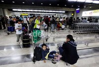 Seorang anak duduk di troli barang didampingi ibunya, saat menunggu pengambilan barang.