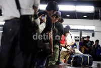 Seorang penumpang tengah mengambil barang bawaan di tempat pengambilan barang.