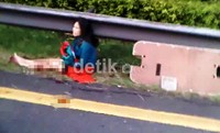 Seorang penumpang Luxio yang kakinya berlumuran darah duduk di pinggir jalan. (Rangga Nugraha).