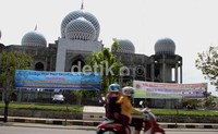 Dua perempuan Lhokseumawe melintas di depan spanduk dukungan terhadap Kebijakan Walikota Lhokseumawe di depan Masjid Islamic Centre Kota LHokseumawe. Feri Fernandes/detikFoto.