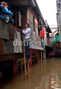 Seorang warga naik ke lantai dua menggunakan tangga.