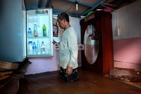 Agar tidak terendam, seorang warga mengevakuasi kulkasnya ke atas meja.