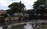 Ekscavator mengeruk lumpur dari dasar Sungai Ciliwung di kawasan Pasar Baru.