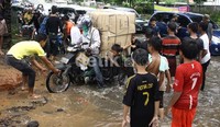 Sejumlah anak-anak menawarkan jasa untuk  memolong para  biker untuk menghindari genangan air. Ramses/fetikfoto
