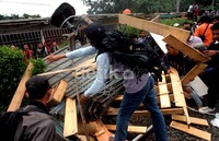 Penumpang KRL membersihkan kayu-kayu yang sebelum dipasang di rel oleh pedagang dan mahasiswa.